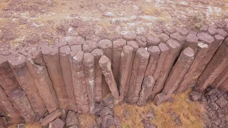 Broken-along-cliff,-unstable-volcanic-basalt-column-leans-on-others