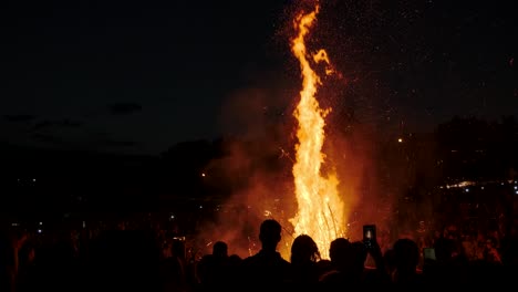 people stand around a big bonfire at a festival