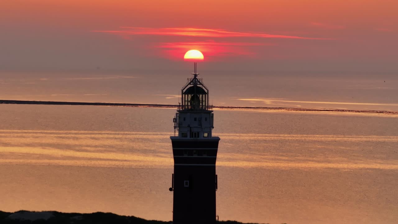 Vista aerea del faro di Westhoofd al tramonto drammatico con colori caldi sulla spiaggia e sul Mare del Nord a Ouddorp