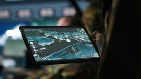 agente militar trabajando en la sala de control, usando software en la tableta