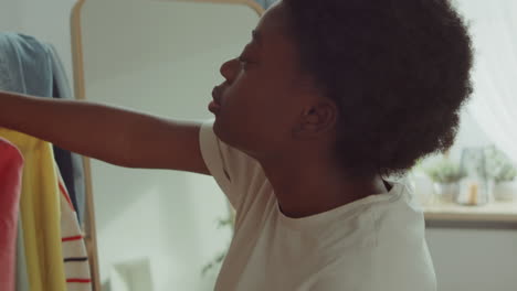 joven mujer afroamericana eligiendo ropa en casa