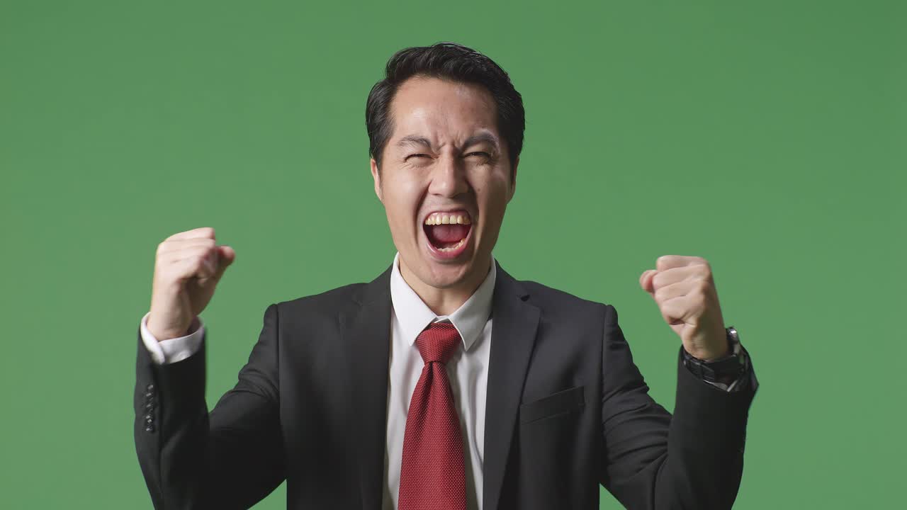 행복 한 아시아 사업가 는 스튜디오 에서 녹색 스크린 에 서서 축하 하고 있다