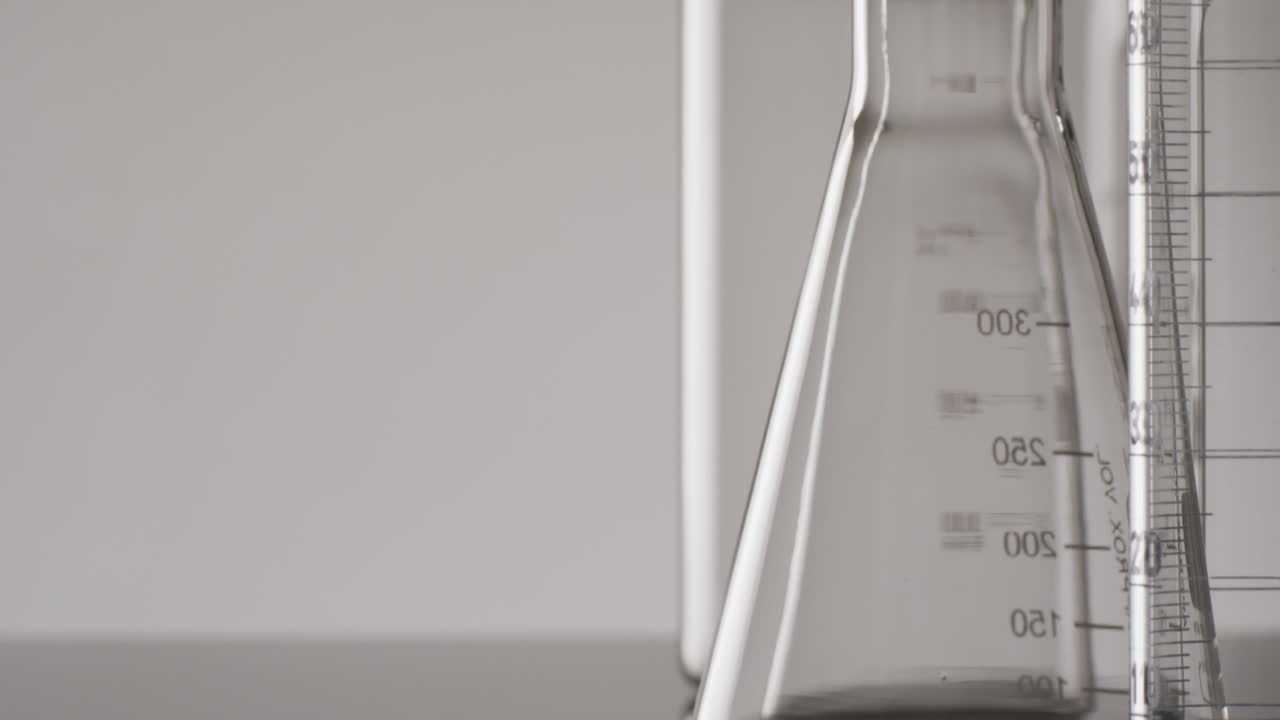 Video of close up of glass laboratory beakers and dishes with copy space on white background