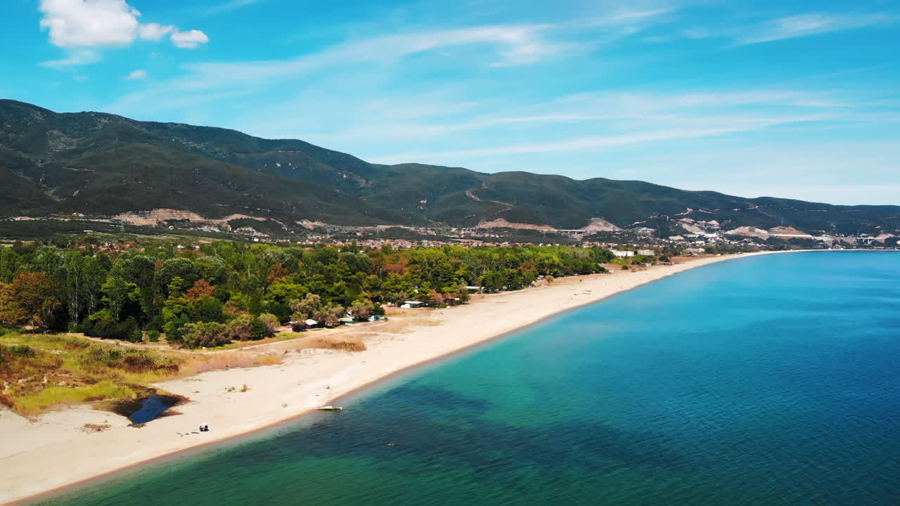 Panorama of Aegean sea coast with greenery, green hills on the background. Long beach. Sunny day. Asprovalta, Greece