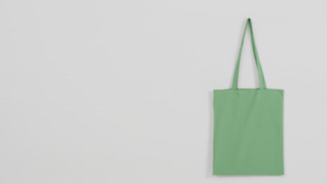 Close-up-of-green-bag-on-white-background,-copy-space,-slow-motion