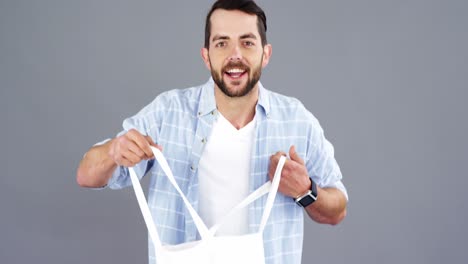 hombre sosteniendo una bolsa de mano sobre fondo gris