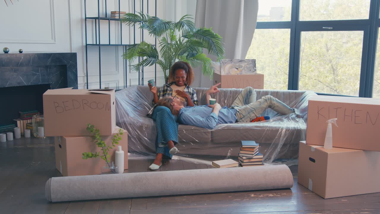 Joy couple relax on sofa after moving into cool apartment with good renovation