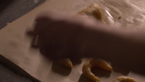 close up, woman's hands rolling cookie dough and shaping into crescent shape