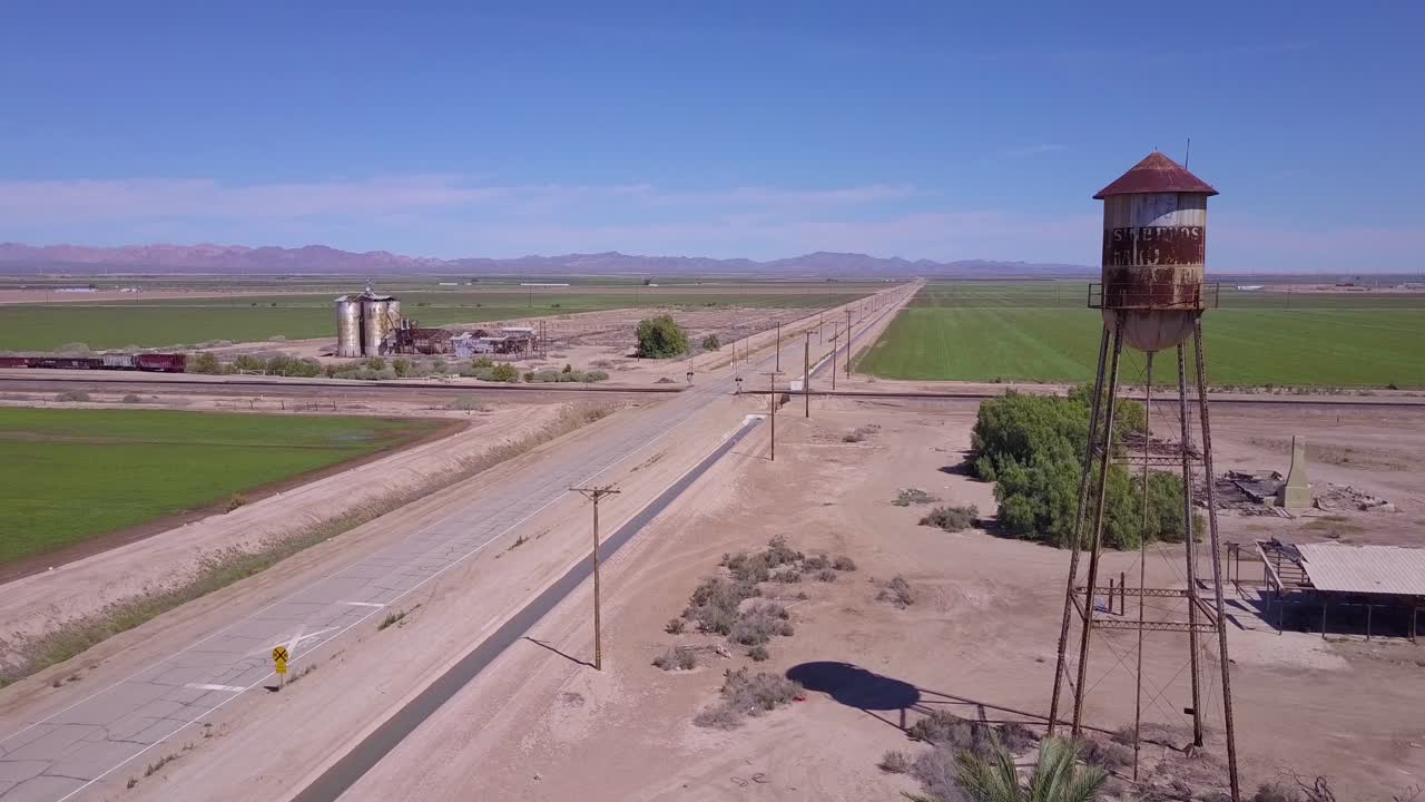 급수탑 전경이 있는 시골 지역을 통과하는 외로운 버려진 도로 위의 높은 각도의 공중