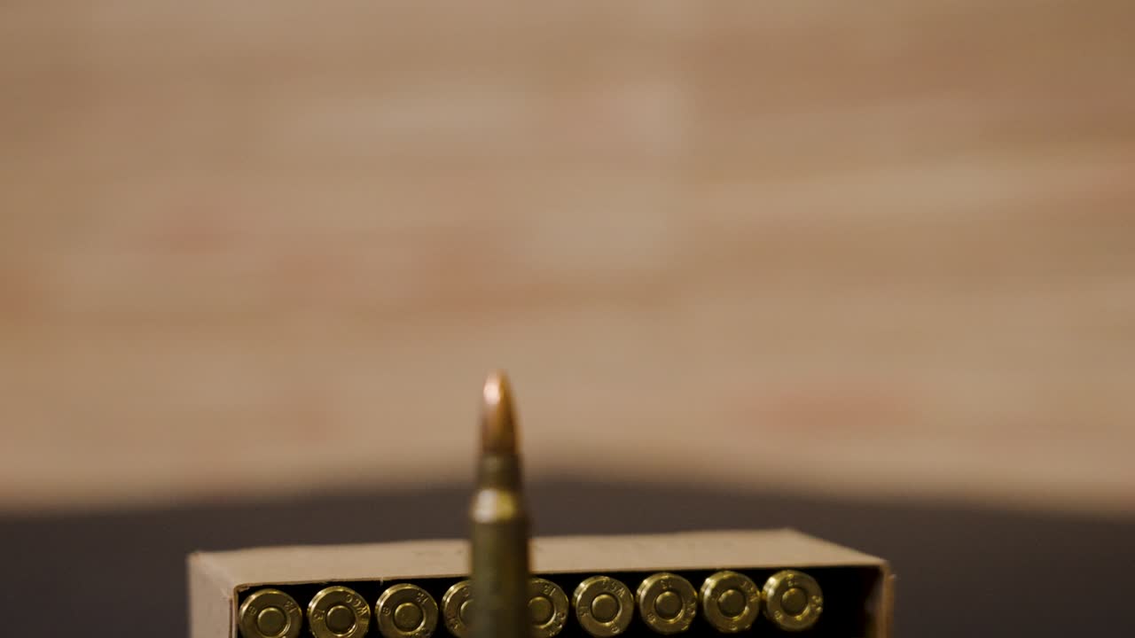 Close-up of a Single Bullet with a Box of Ammunition in the Background