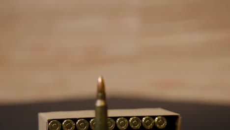 close-up of a single bullet with a box of ammunition in the background
