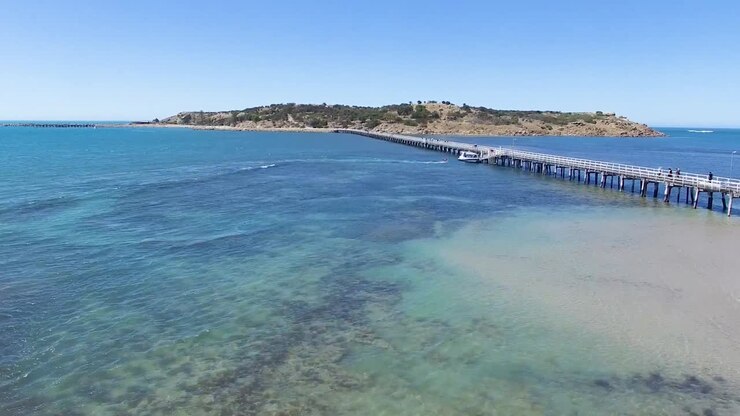 Ripresa aerea bassa che si muove verso l'originale strada rialzata di Granite Island a Victor Harbor, Australia Meridionale