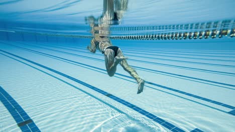 mujer nadando en la piscina en la piscina olímpica vista desde debajo del agua