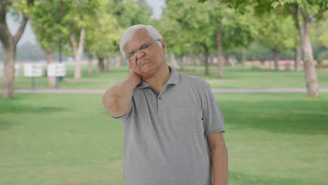 Sick-Indian-old-man-having-a-neck-pain-in-park