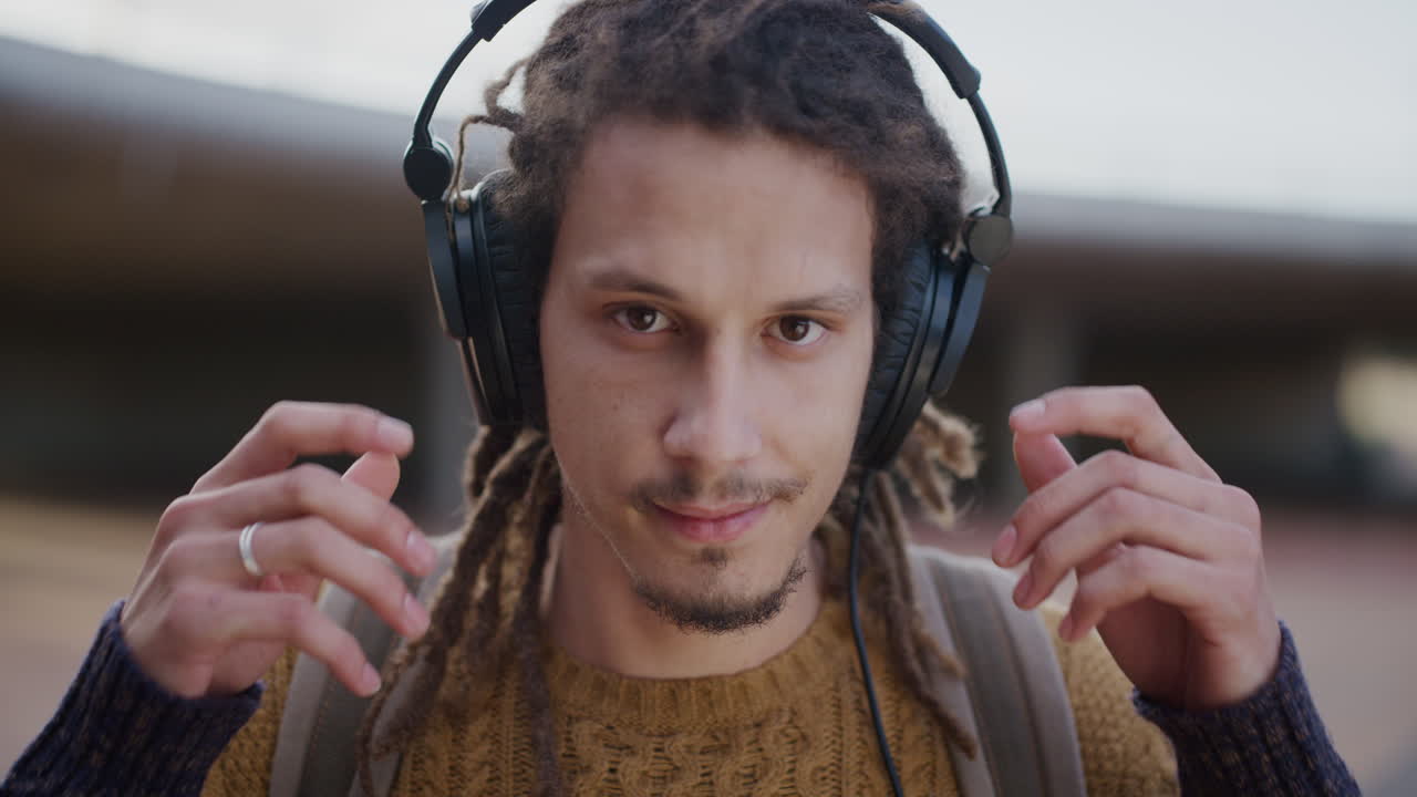 retrato de cerca relajado joven de raza mixta hombre se quita los auriculares sonriendo confiado disfrutando de un estilo de vida exitoso satisfacción