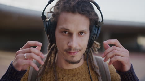 close up portrait relaxed young mixed race man takes off headphones smiling confident enjoying successful lifestyle satisfaction