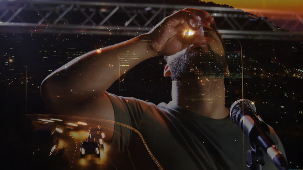 male performer sipping shot glass by microphone at lighting truss, showing entertainment concept