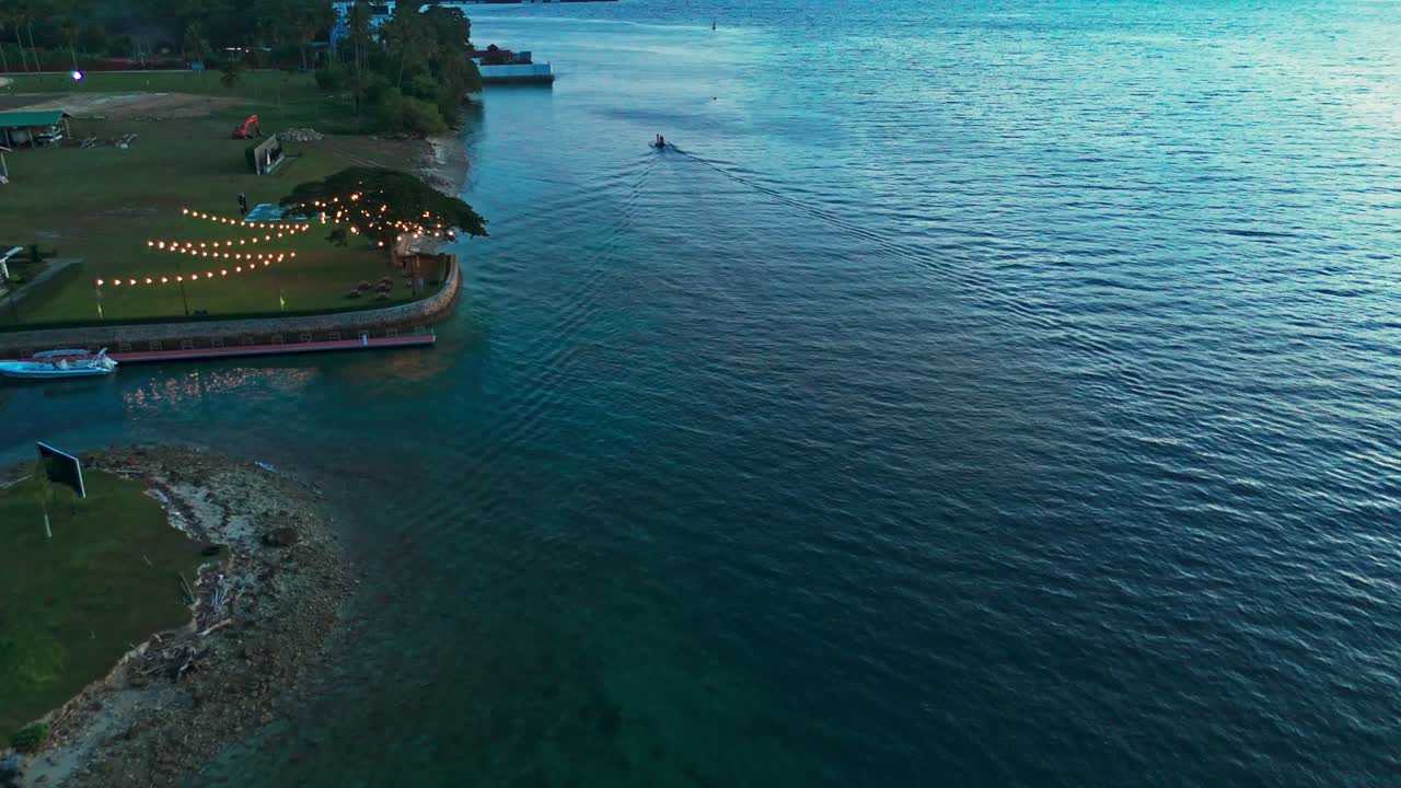 A stunning aerial view of a boat sailing through the calm, clear waters of the Philippines. Captured during the early morning, this footage highlights natural coastal beauty and tranquil ocean vibes