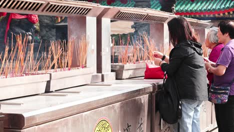 people lighting incense sticks at a temple