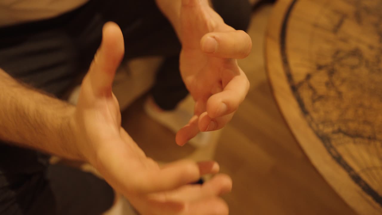 Close-up of a man holding a smartphone that suddenly slips from his hands and falls to the floor in slow motion. Warm indoor lighting, realistic everyday mishap