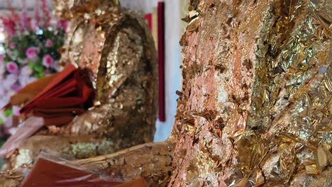 gold leaf application on buddha statues in a thai temple