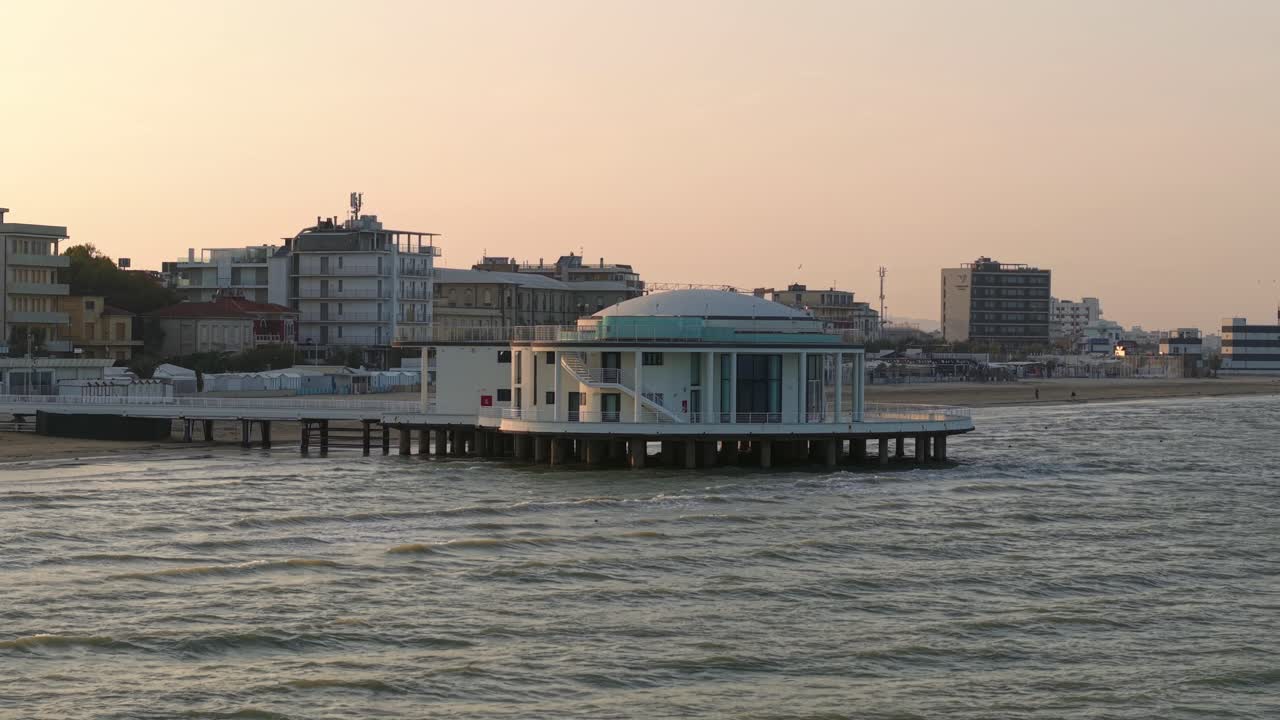 Low sunset drone orbit of landmark rotunda and pier in Senigallia, Italy