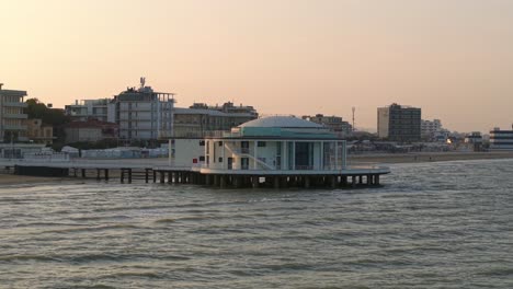 low sunset drone orbit of landmark rotunda and pier in senigallia, italy