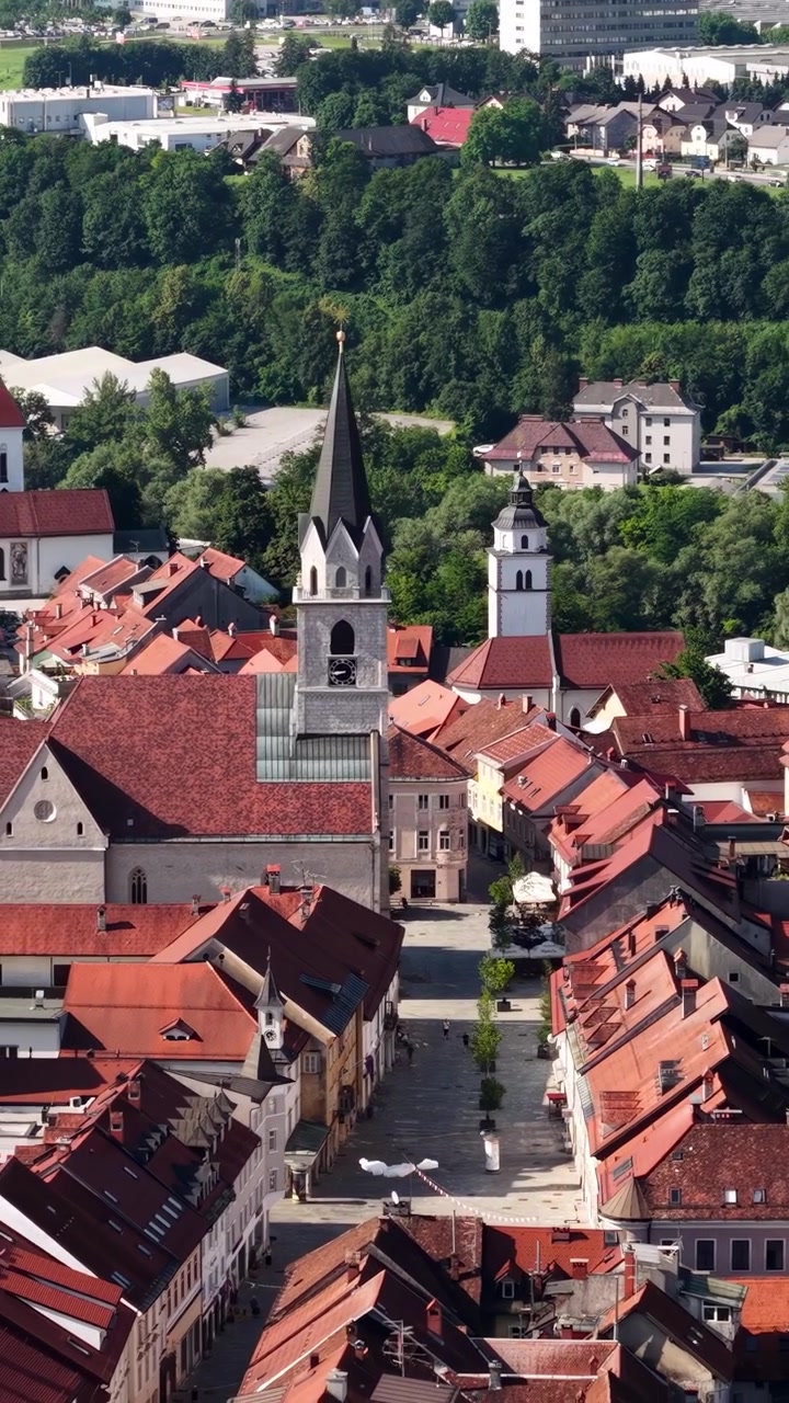 Ripresa verticale con drone di Kranj, Slovenia. Edifici del centro storico e torri di chiese in una soleggiata giornata estiva