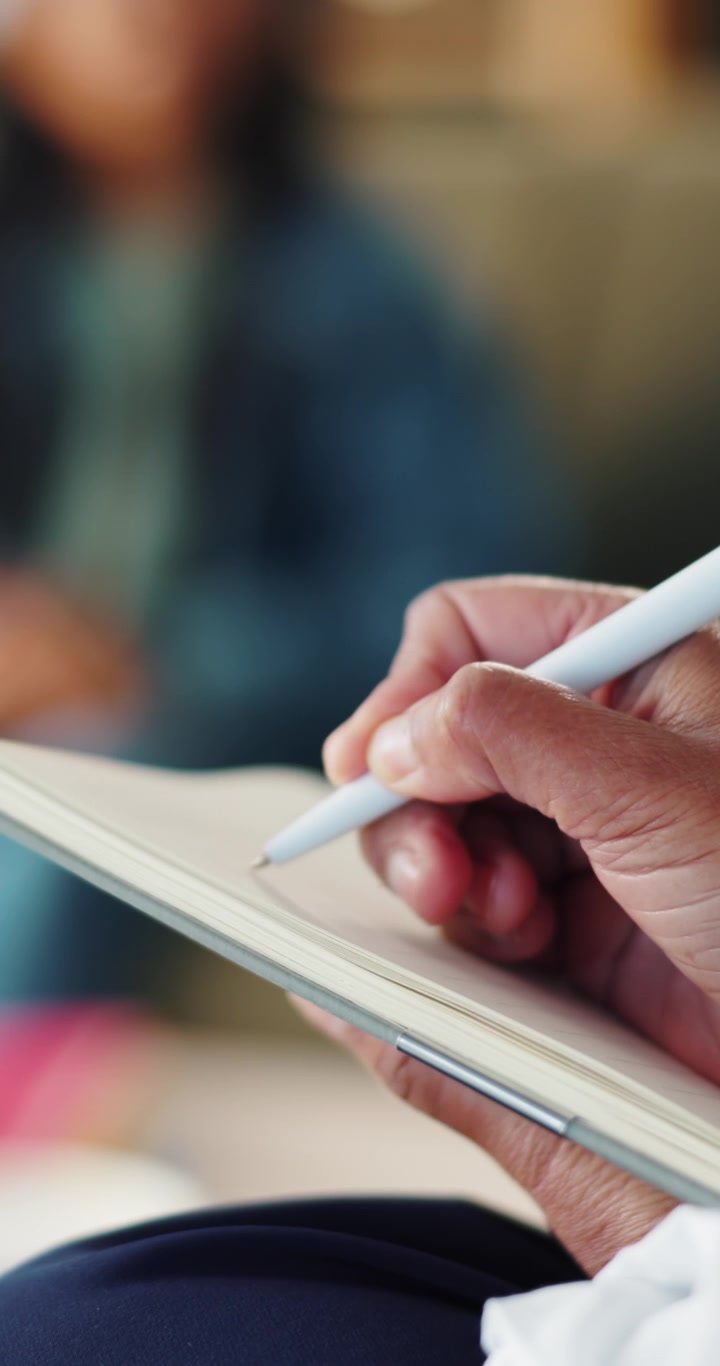 Close-up of Person Writing in Notebook with White Pen