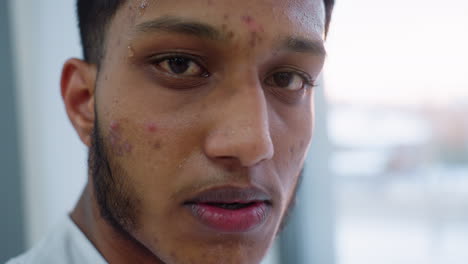 close up profile of young man resting after intense treadmill sprint, sweat dripping, red tired eye, blurred window behind shows outdoor cityscape glow, headphone perched on neck, recovery moment