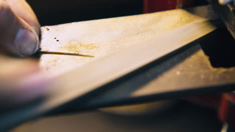 jeweler polishes gold rod and cleans workplace closeup