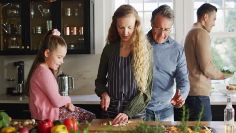 video of happy caucasian parents and daughter having fun cooking with grandfather in kitchen
