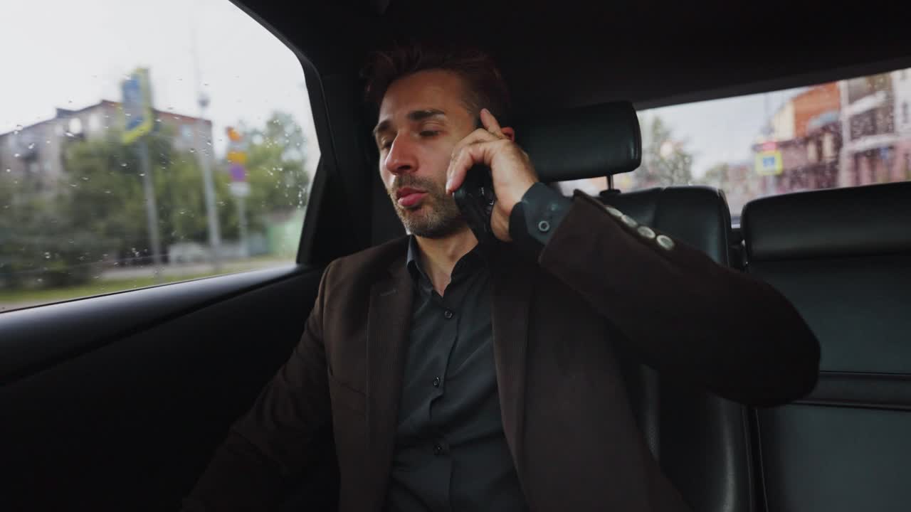 Forretningsmand taler i telefon i en bil