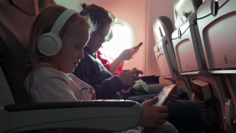 familia de madre y dos niños con aparatos en el avión