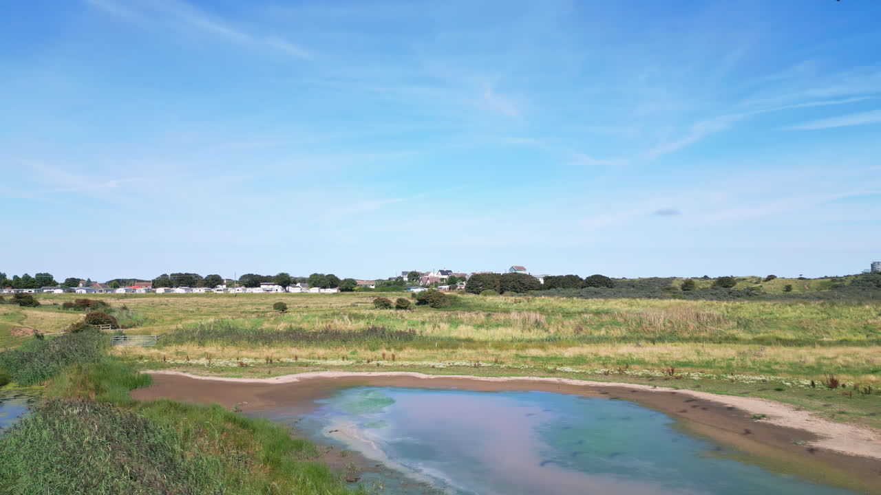 por encima del terreno costero, las imágenes de video ofrecen una vista de las tranquilas marismas de agua salada de la costa de lincolnshire, con aves marinas volando graciosamente y descansando en las lagunas y lagos interiores