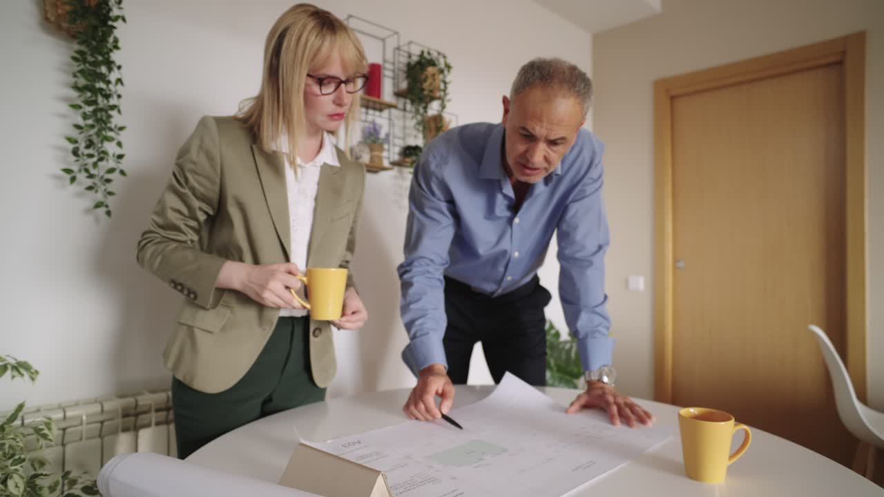 Two people discussing a blueprint at a table