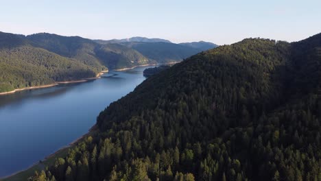 Drone-rising-over-a-forest-to-reveal-a-snaking-river-in-a-mountain-valley