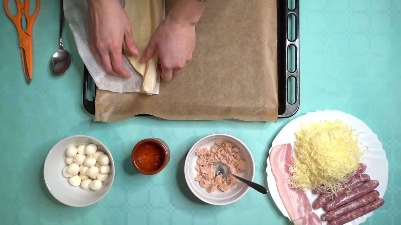 mujer abriendo y colocando masa de pizza en una bandeja para hornear desde la vista superior