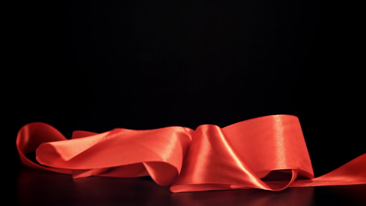 Nastro di raso rosso che cade e forma un cappio su sfondo nero
