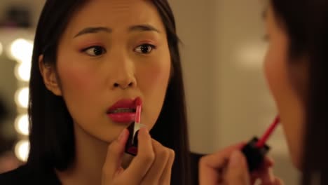 a serene beauty moment captured in a makeup routine, showcasing a young woman skillfully applying vibrant lip color while gazing at her reflection in a mirror