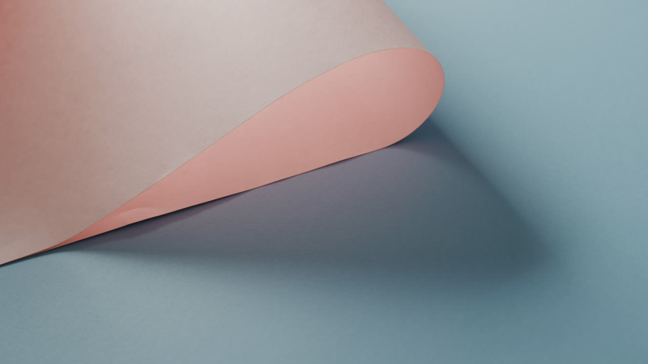 Close up of pink rolled paper on blue background with shadow and copy space, in slow motion