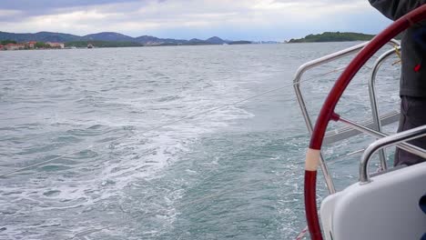 hand of helmsman steering helm of a yacht sailing on the sea - medium shot