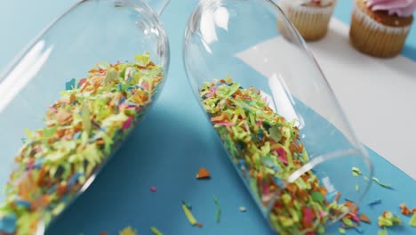 Champagne glasses with confetti and white card on blue background at new year&#039;s eve