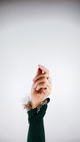 la mano de la mujer que se extiende hacia arriba, adornada con accesorios inspirados en la naturaleza