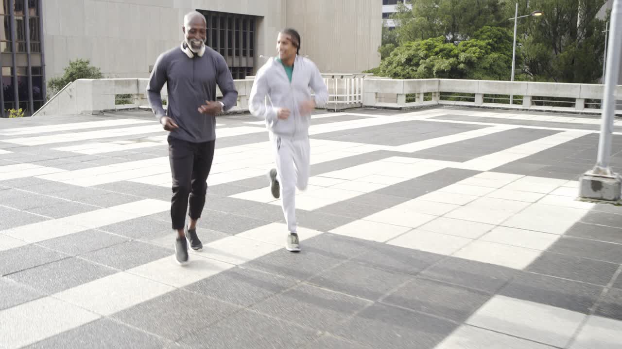 Diversi amici uomini che si salutano, si riscaldano per la corsa, controllano gli smartwatch e fanno jogging sul tetto