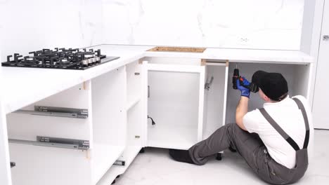 a qualified craftsman in gray overalls installs furniture using a construction laser a qualified craftsman in gray overalls installs furniture using a construction laser