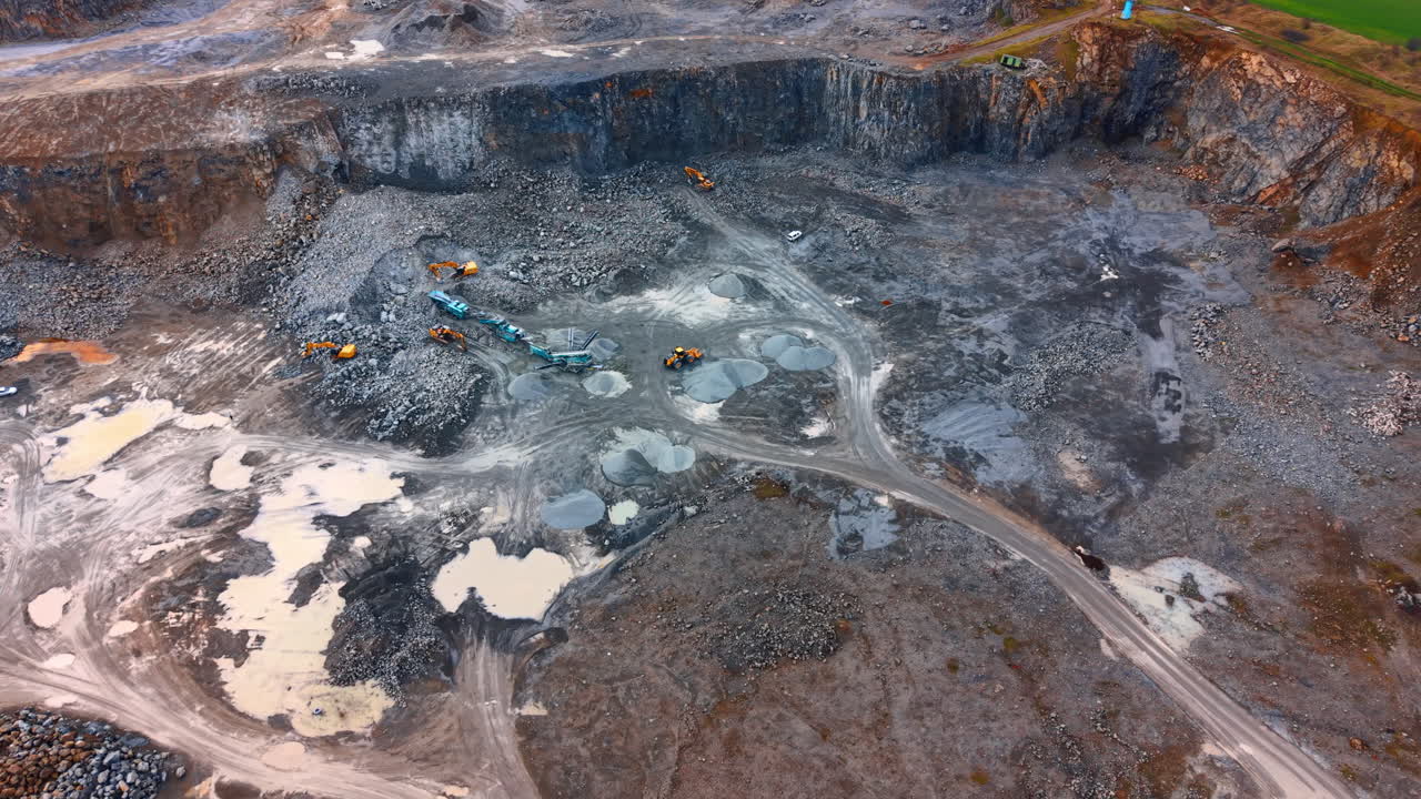 Construction site with equipment. Heavy machinery works in a large gravel pit. Trucks move rocks and dirt during the daytime in an active mining area