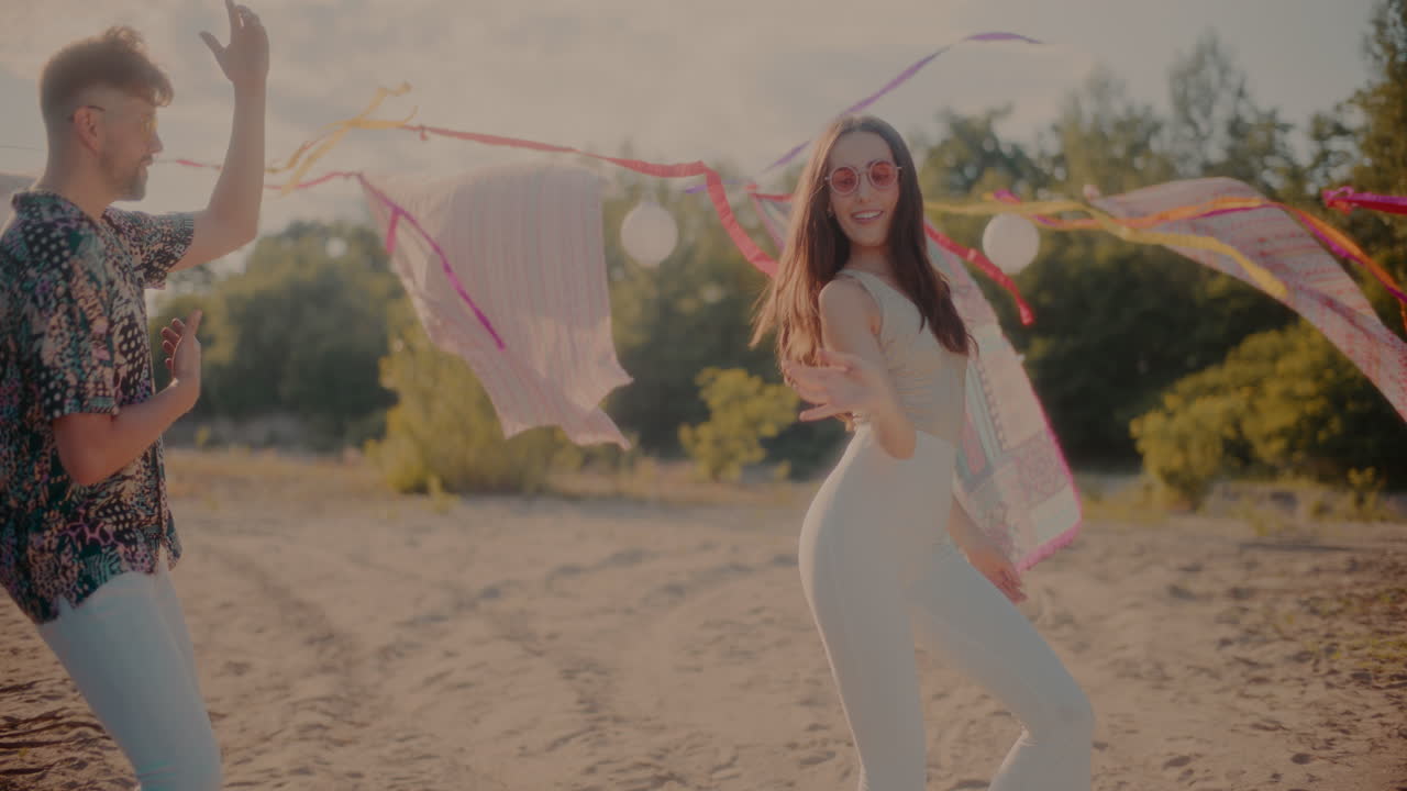una joven pareja bailando bachata contra sarongs colgados en la playa