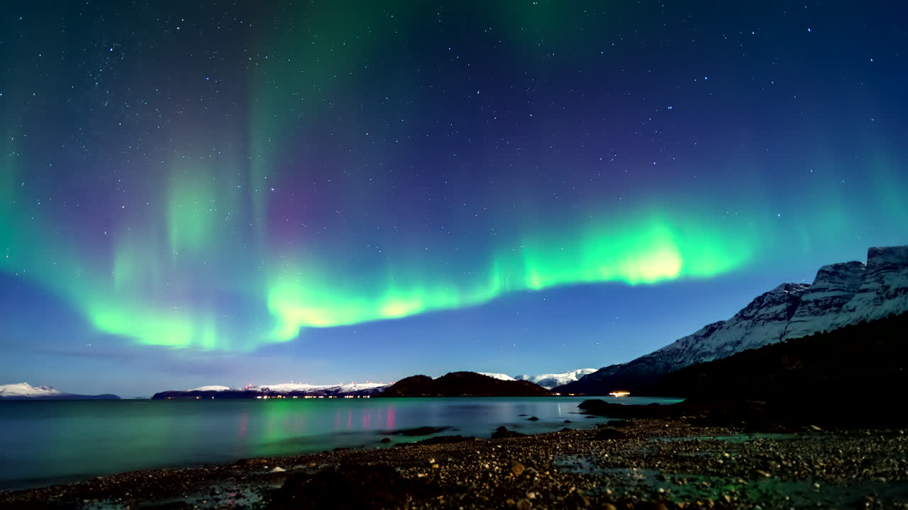 Ethereal northern lights dance in Norway night sky, view from beach. Timelapse