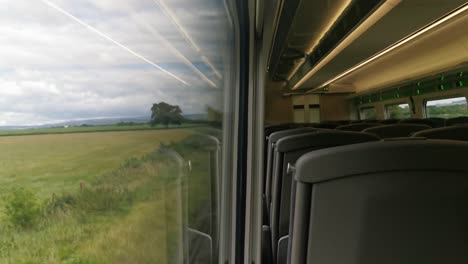 a view of an empty uk train travelling with a view from within a train carriage and partially the outside view from the train window